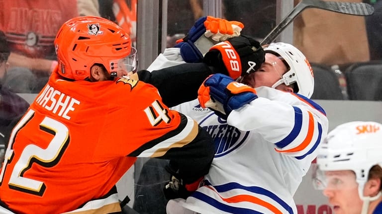 Anaheim Ducks center Tim Washe, left, puts a hit on...