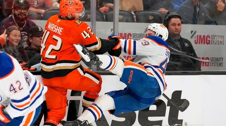 Anaheim Ducks center Tim Washe, left, puts a hit on...