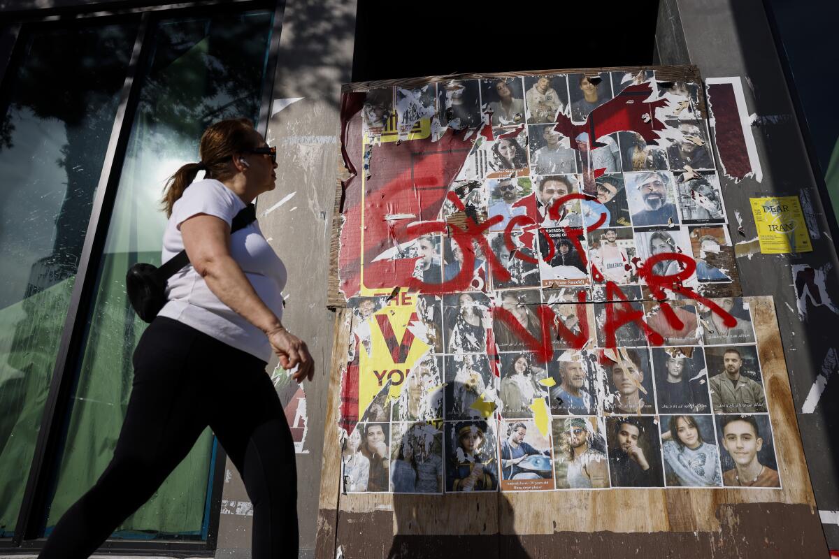 A pedestrian walks past photographs of Iranians killed along Westwood Boulevard