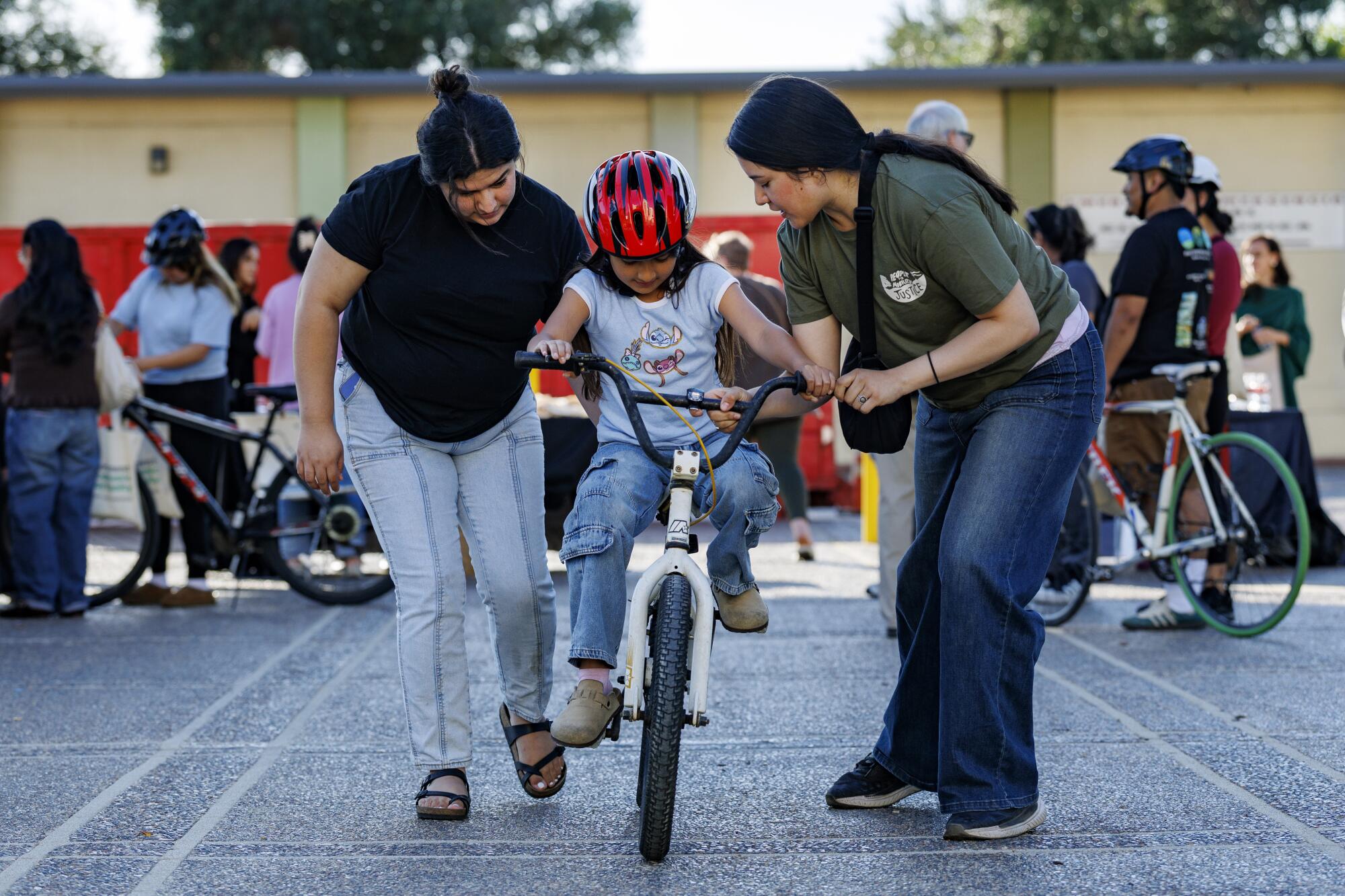 Two women help a young girl ride a bike for the first time in Los Angeles. 