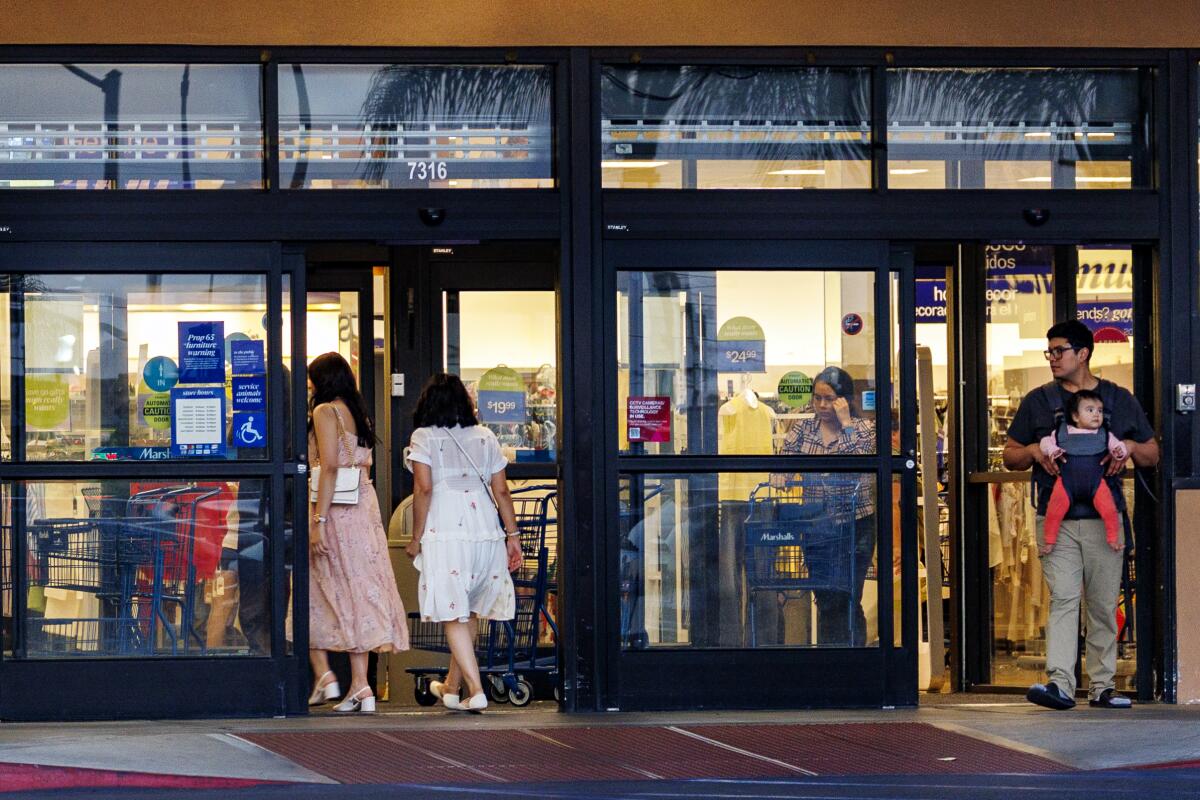 Shoppers enter and leave a discount clothing store at Plaza La Alameda.