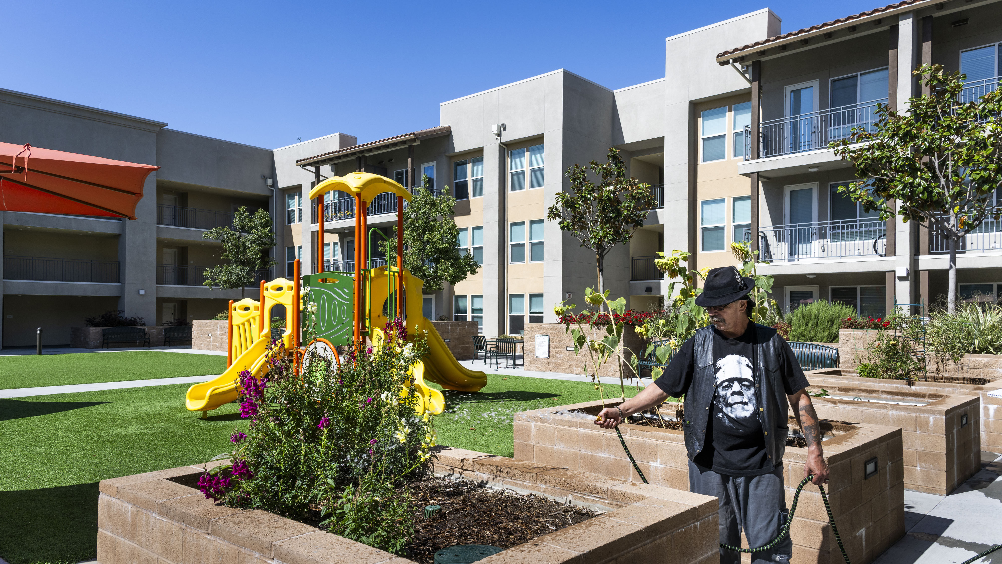 Resident Kevin Weber waters the gardens at Legacy Square in...