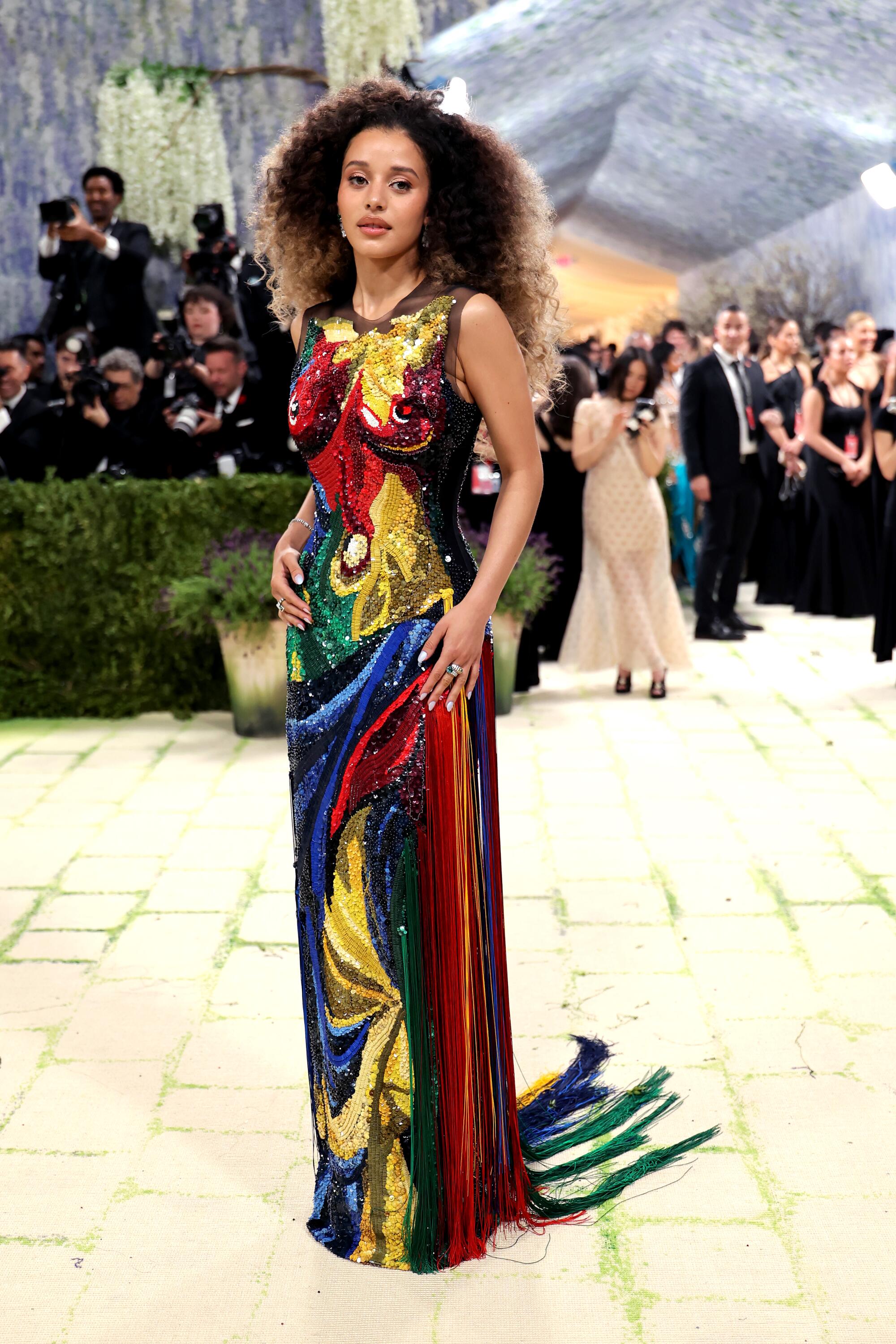 Chase Infiniti, wearing a colorful sequin dress, poses at the Met Gala. 