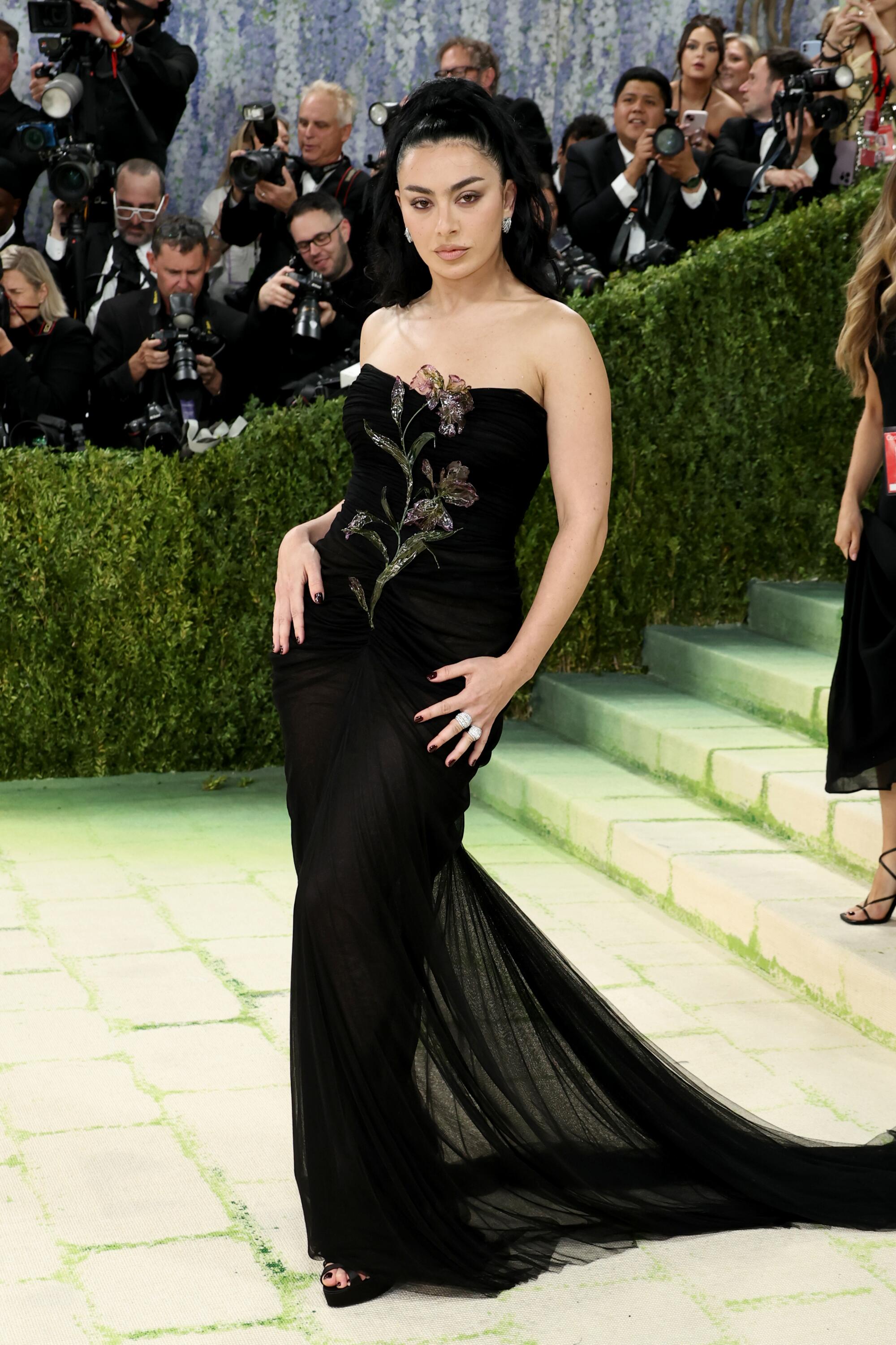 Charli XCX, wearing a black gown, poses at the Met Gala. 