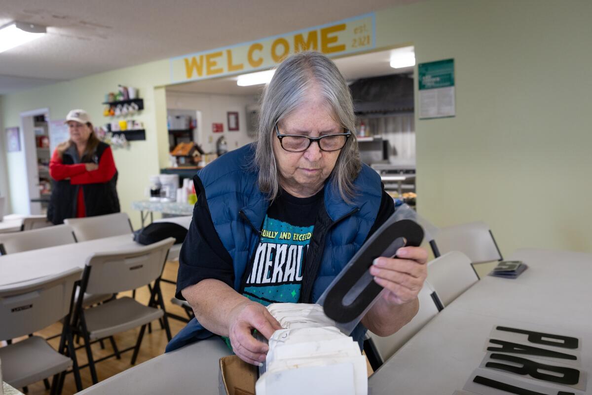 a woman with gray hair organizes letters for a road sign