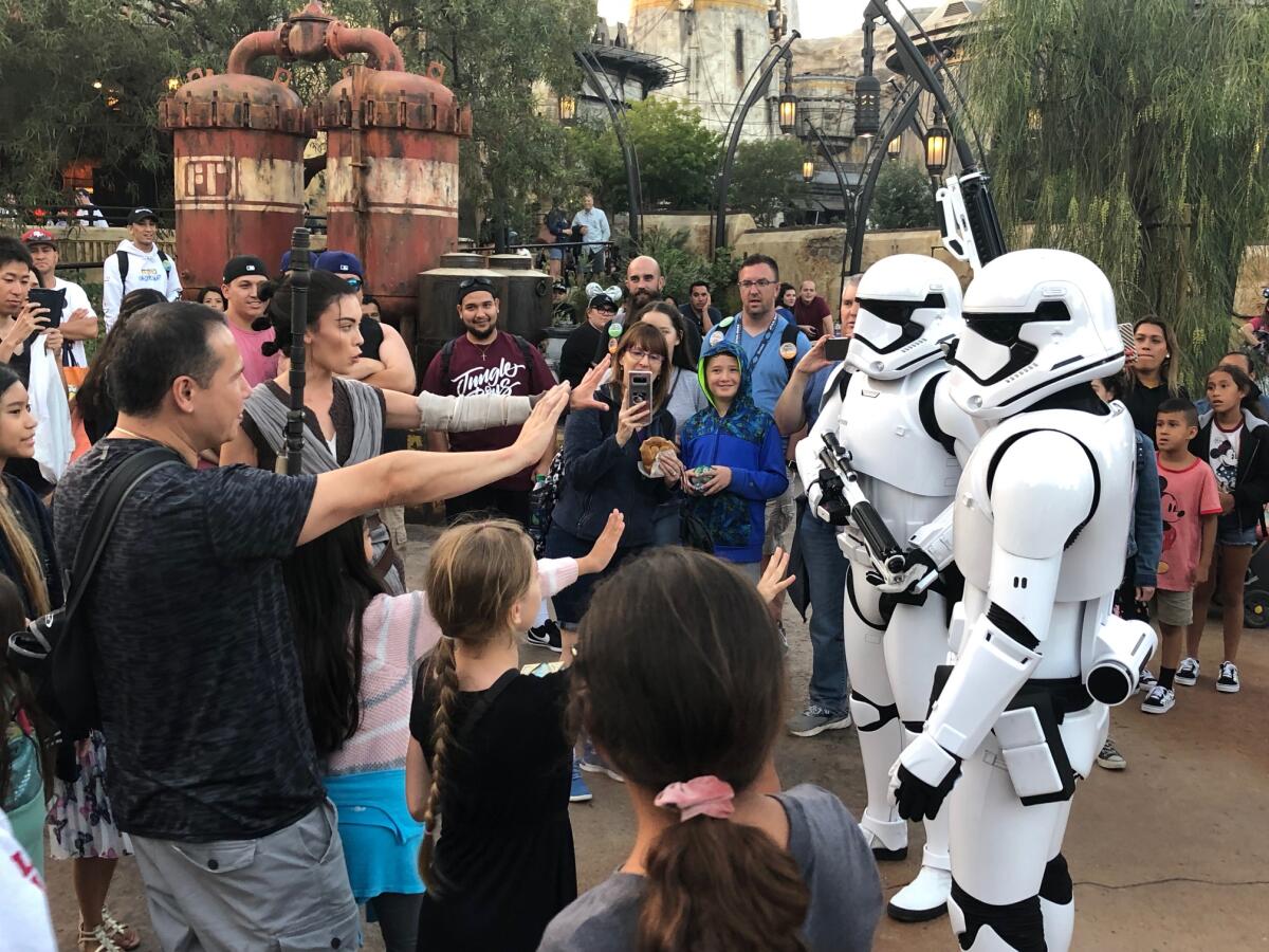 Parkgoers hold up their hands in front of two Stormtroopers.