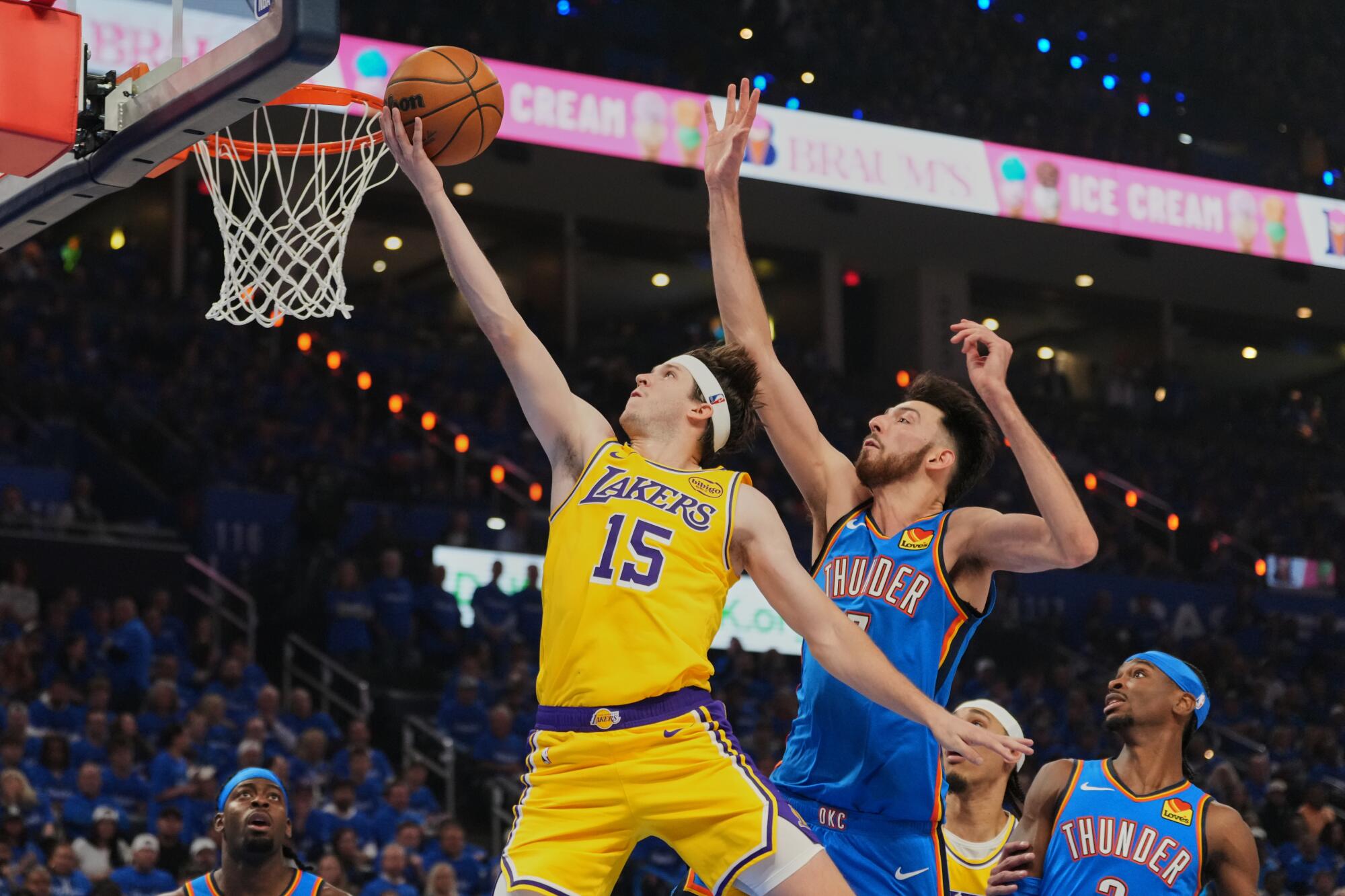 Lakers guard Austin Reaves, left, makes one of his three basketball on a layup past Thunder center Chet Holmgren.