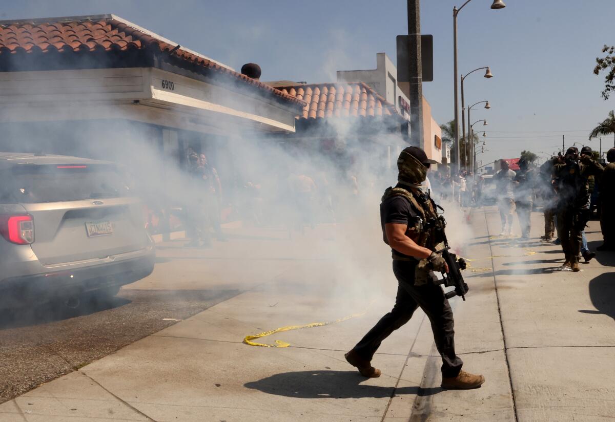 A ICE agent walks through tear gas that was fired to push protesters back