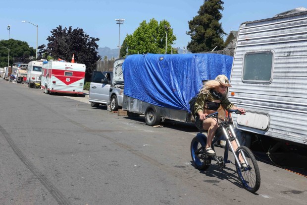 A biker rides past a line of RVs parked at a homeless encampment on Poplar Street in West Oakland, Calif., on Wednesday, April 29, 2026. (Ray Chavez/Bay Area News Group)