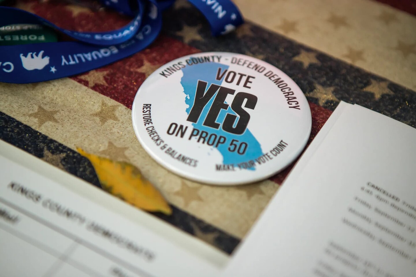 A button reads “Vote Yes on Prop 50” at the Kings County Democrats booth in Hanford on Sept. 25, 2025.