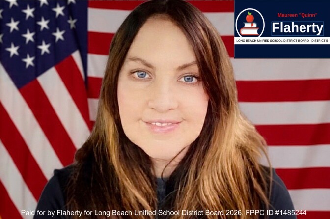 a smiling woman with long brown hair stands against an American flag backdrop