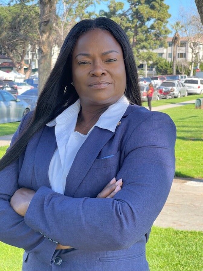a woman with long dark hair wears a blue blazer over a white collared shirt