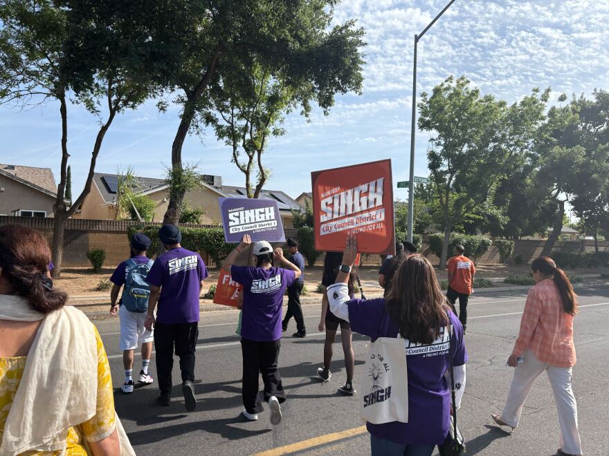 People walking in the middle of W. Gettysburg Ave. in Fresno, holding campaign posters, on the morning of May 2, 2026.