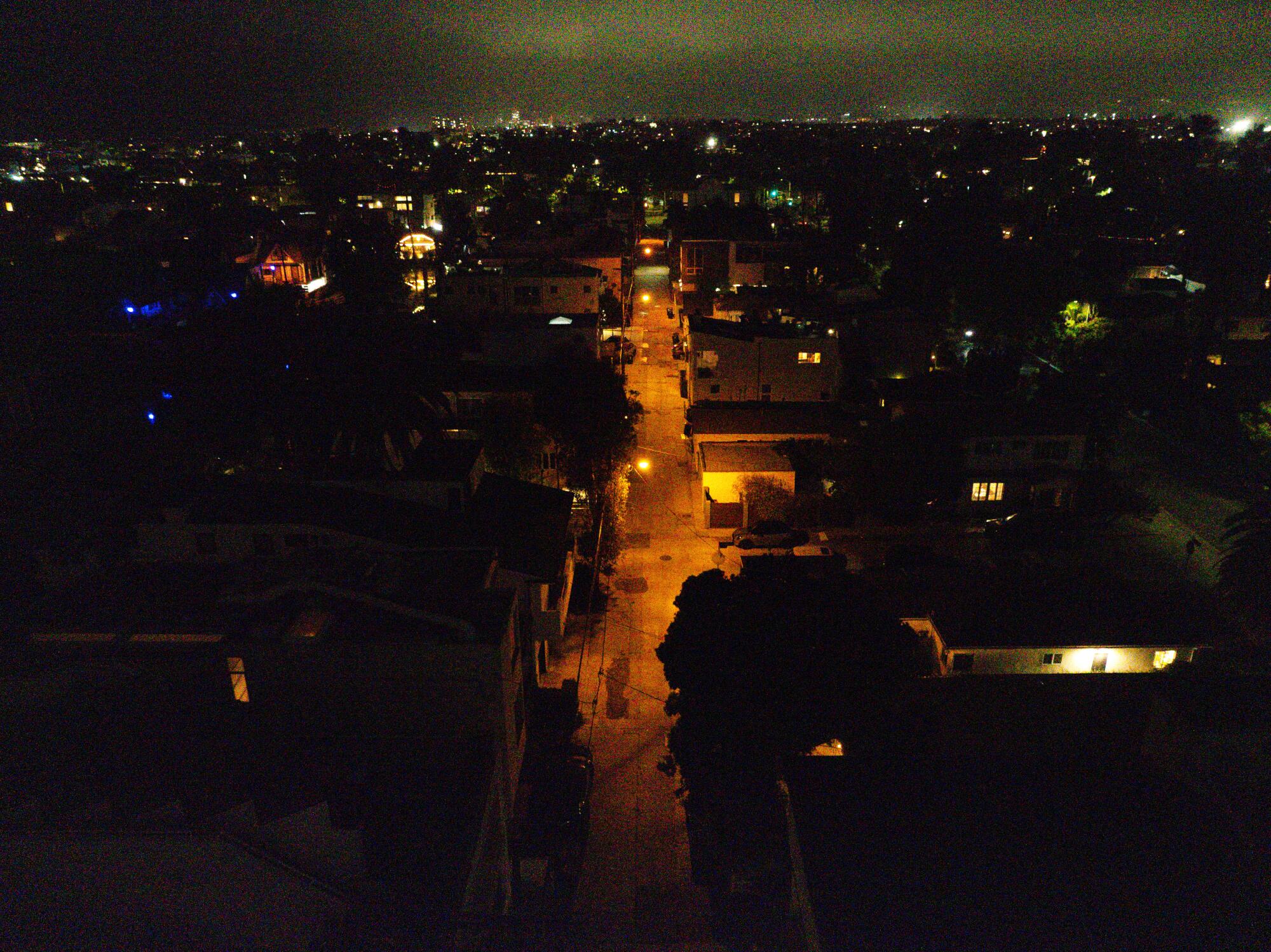 An aerial view of streetlights casting a warm orange glow along a street at night