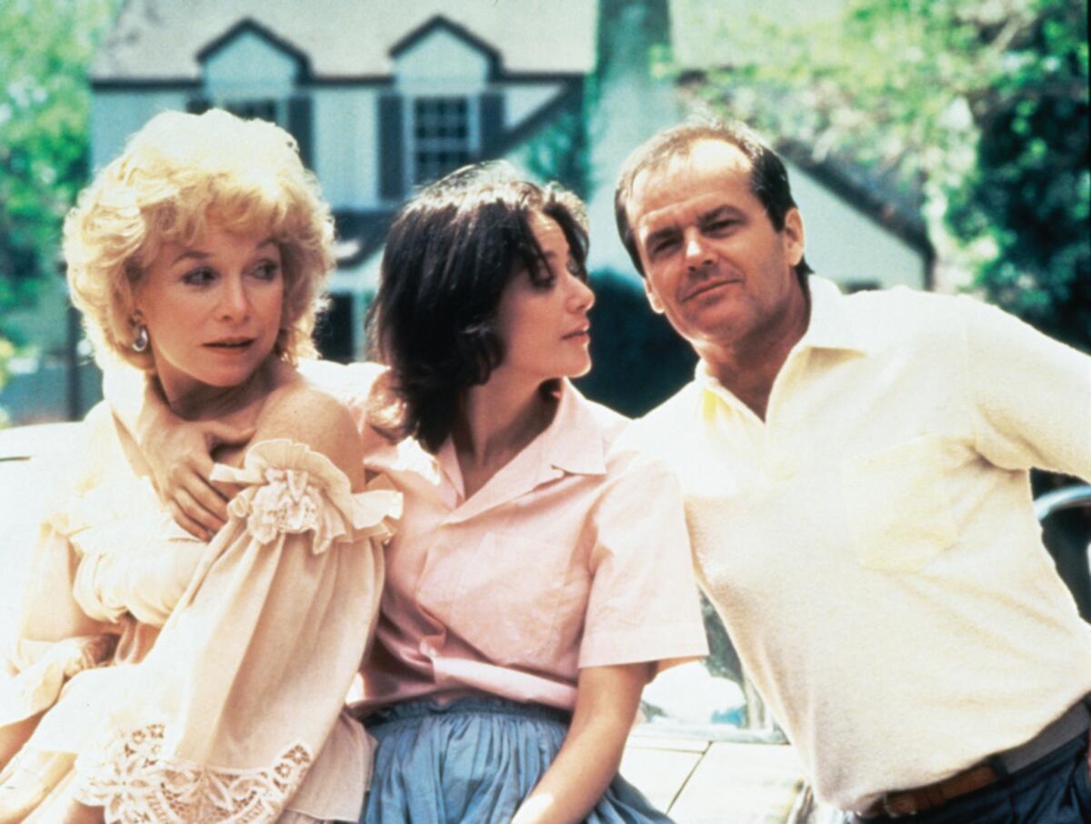 Three people stand in front of a suburban house.