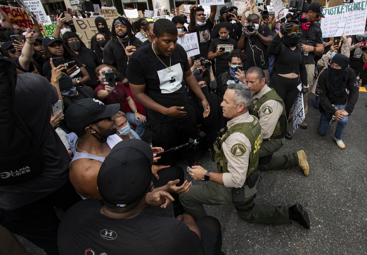 Riverside County Sheriff Chad Bianco takes a knee with demonstrators