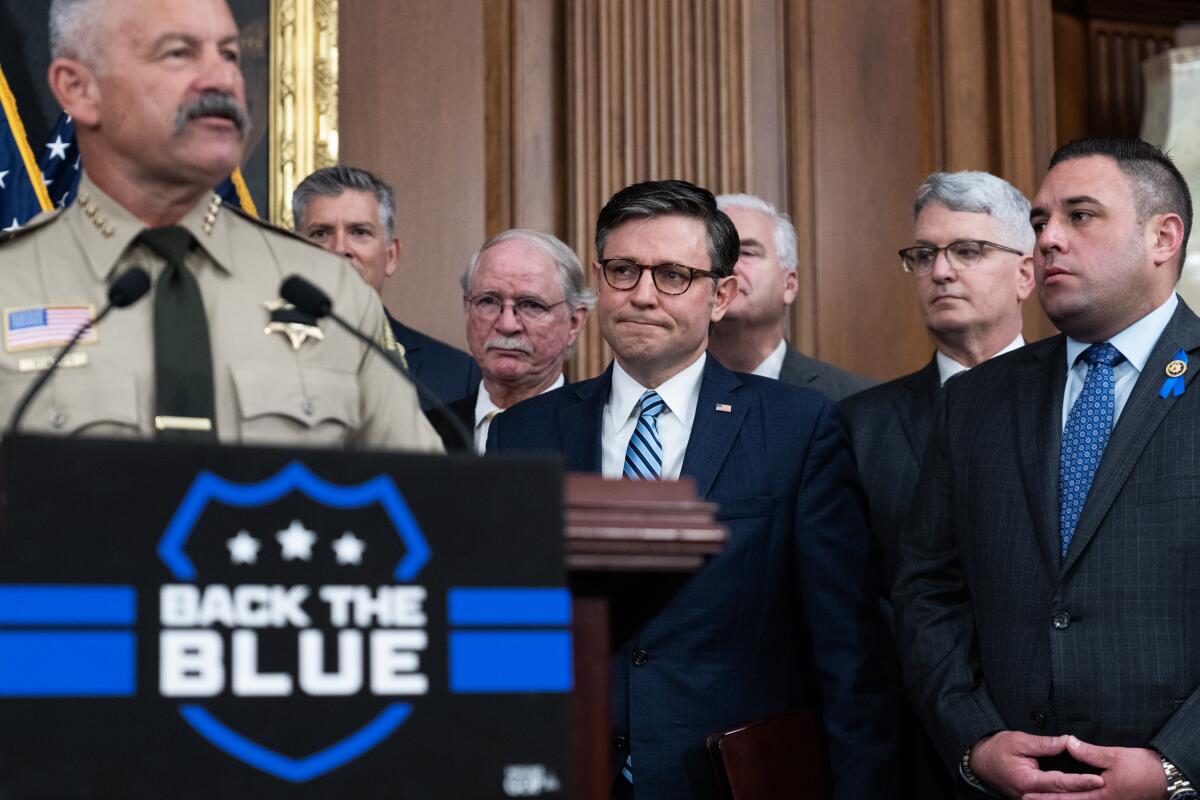 Speaker of the House Mike Johnson, R-La., center, listens to Sheriff Chad Bianco speak