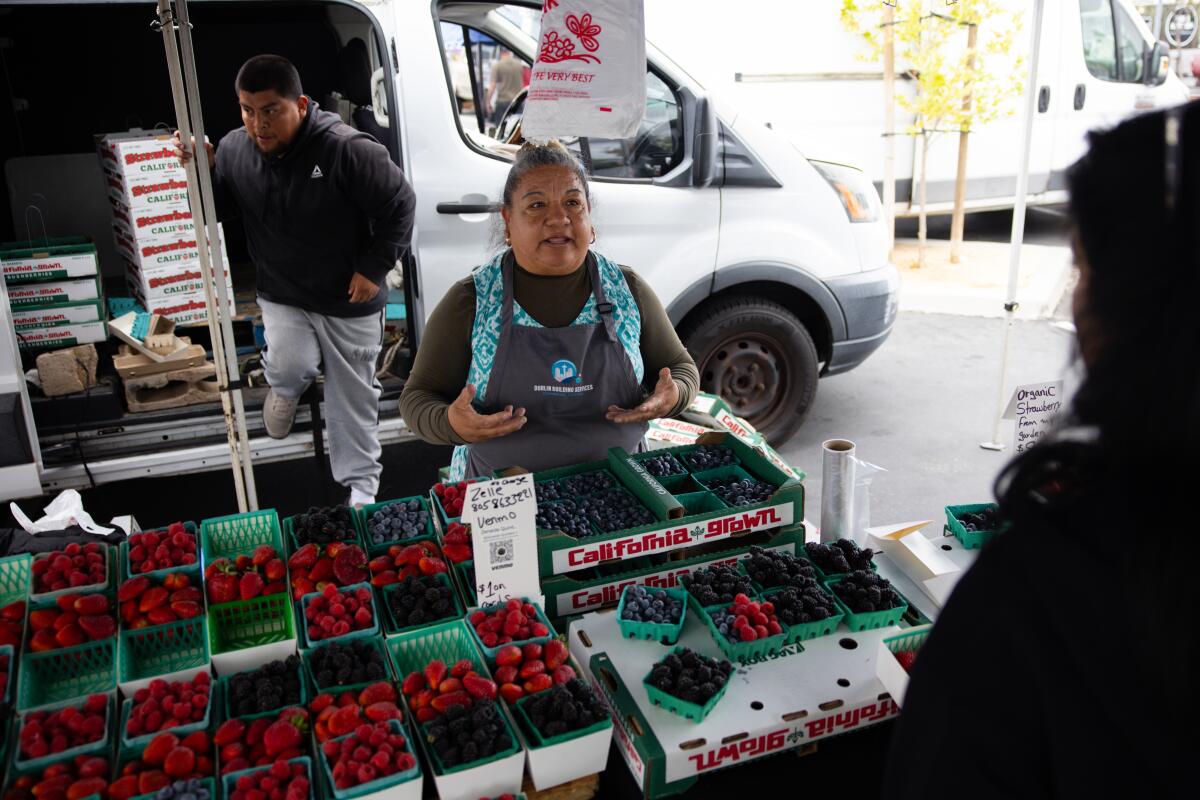 Moises Sanchez, left, and Zenaida Quintero, right, sell berries to customers at the Murrieta Certified Farmer's Market.