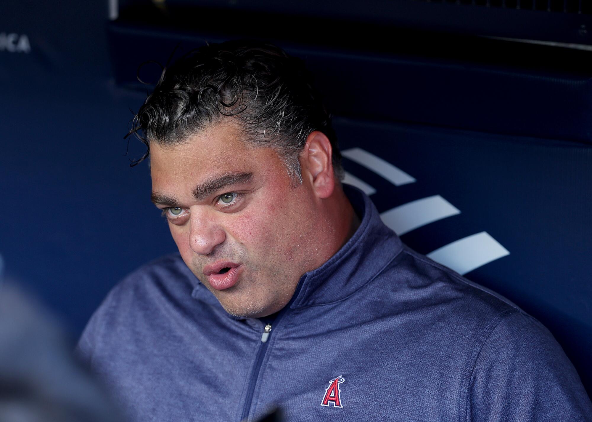 Angels general manager Perry Minasian speaks to reporters in the dugout.