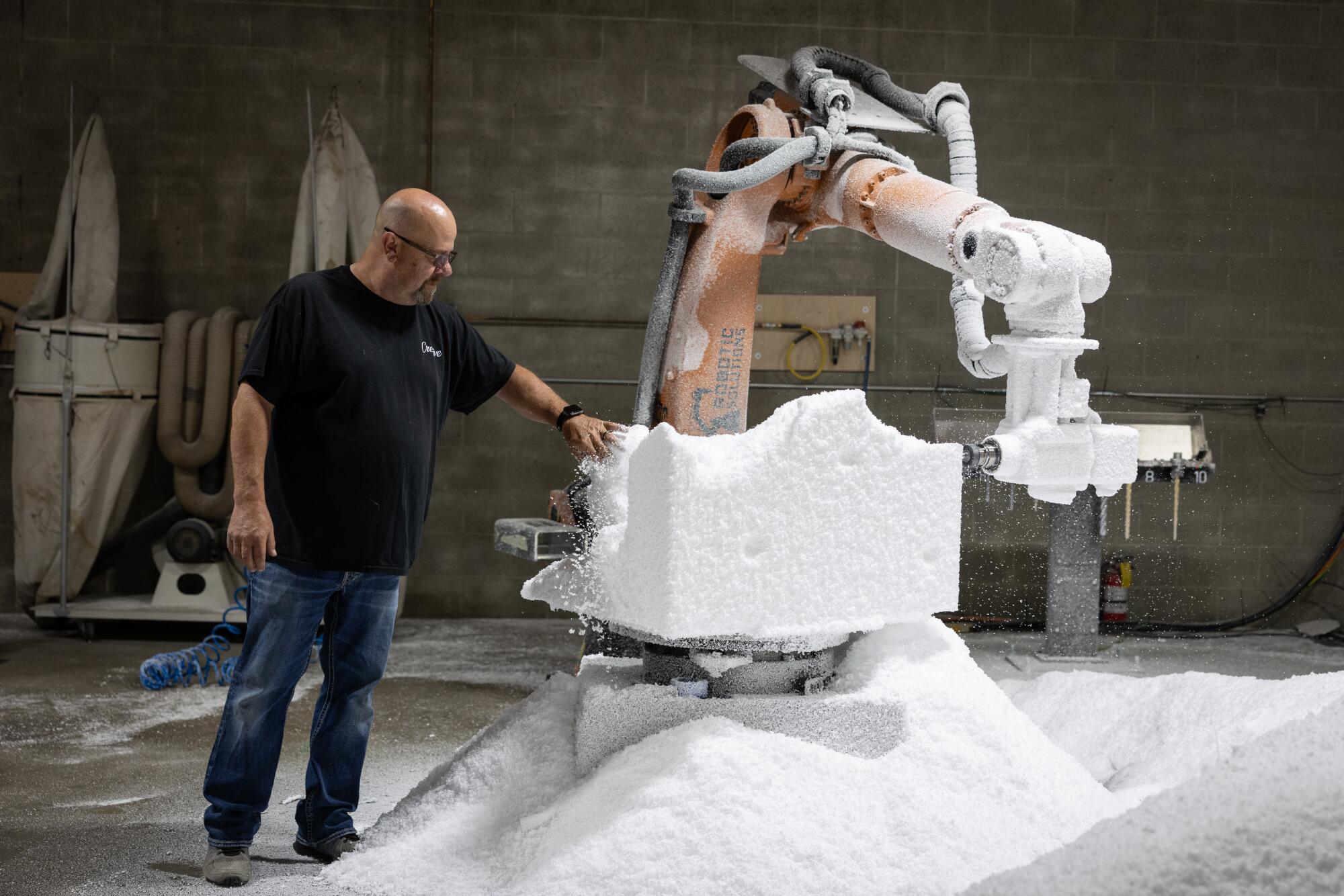 A man checks on a robotic machine as it fabricates at his shop.