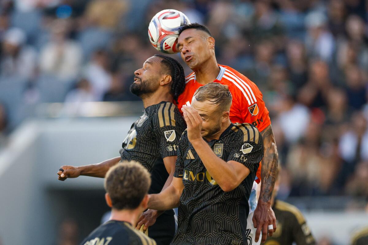 Houston’s Antonio Carlos, top, heads the ball over LAFC’s Eddie Segura, left, and Ryan Porteous.