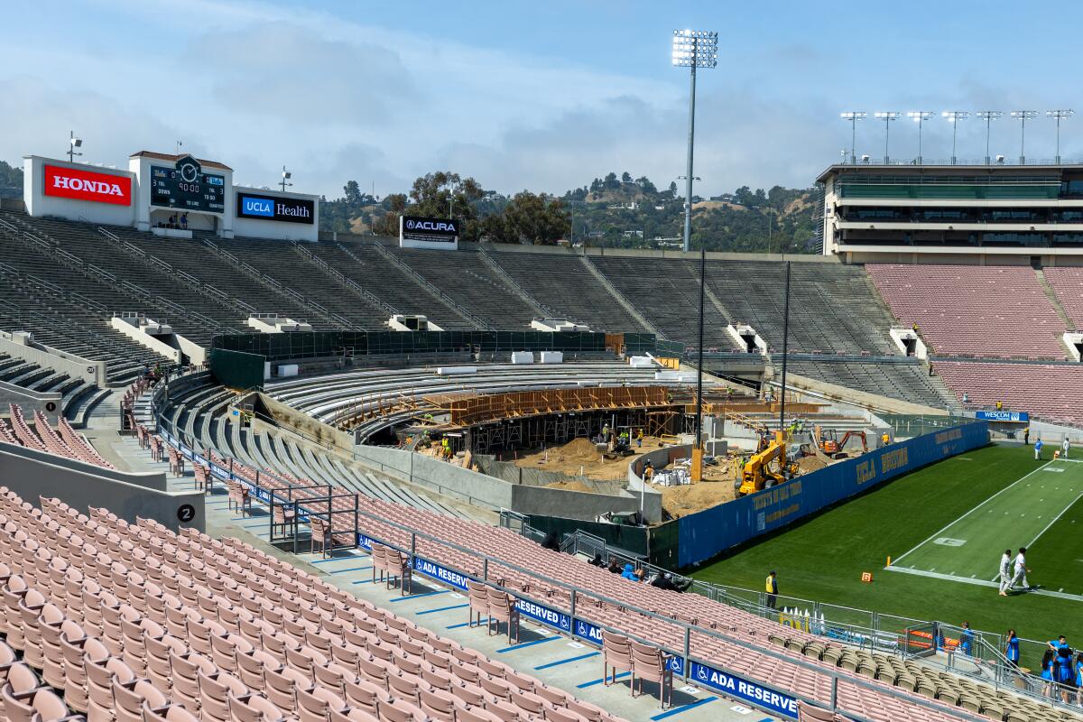 Construction and heavy equipment are seen inside a large open-air stadium.