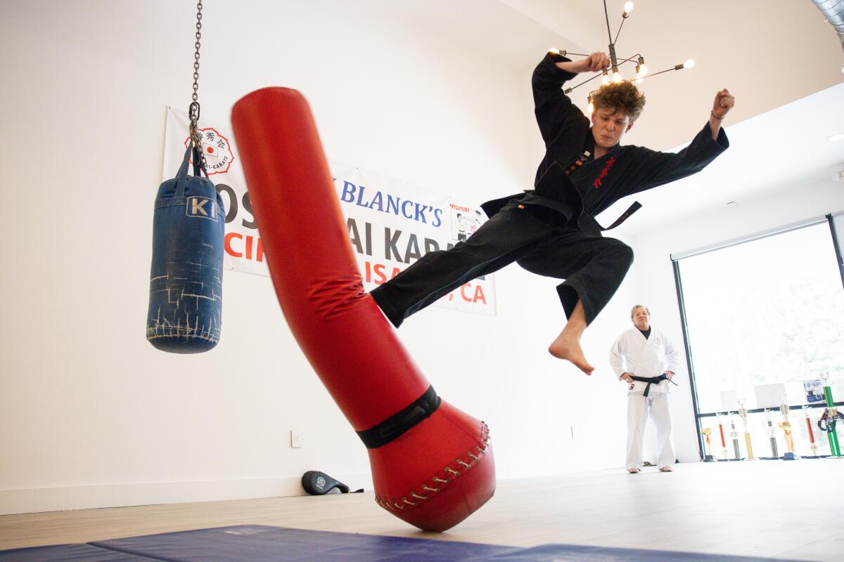 Adam Deloje kicks a punching bag at Blanck's studio.
