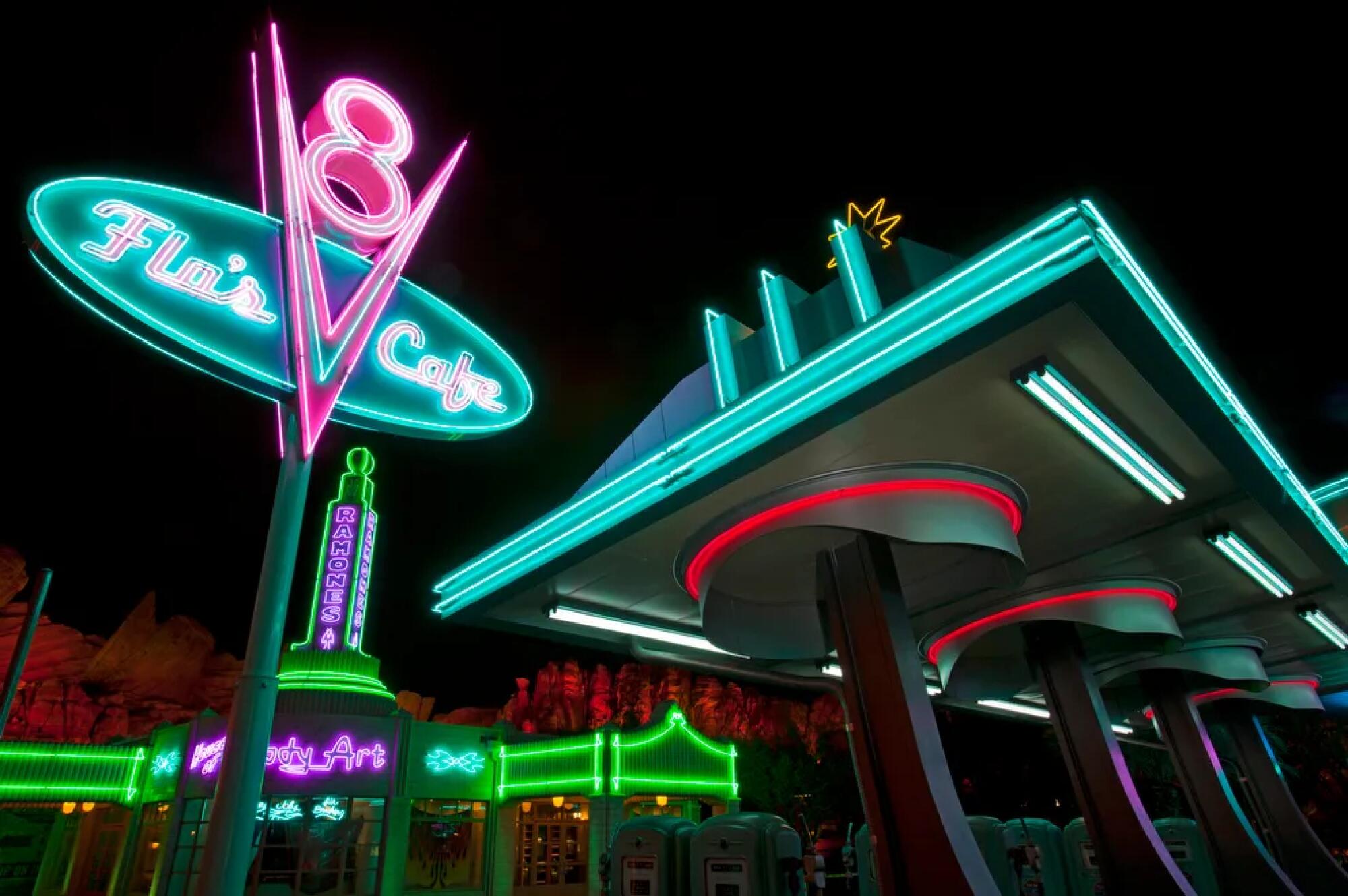 A smattering of neon signs against the night sky in a theme park. 