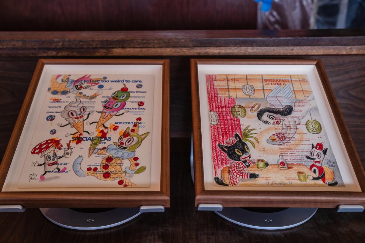 Two framed restaurant menus covered in colorful doodles of ice cream cone and cat characters.