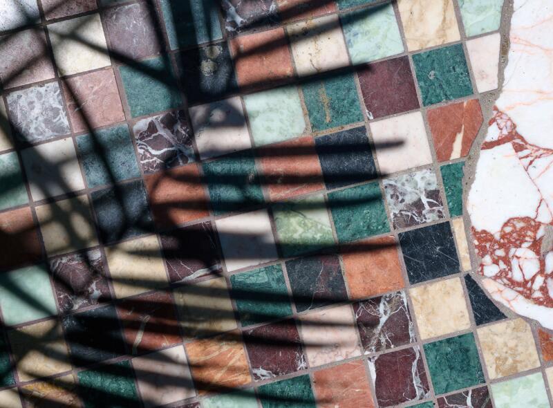 A shadow is cast on marble flooring in courtyard near oyster bar.