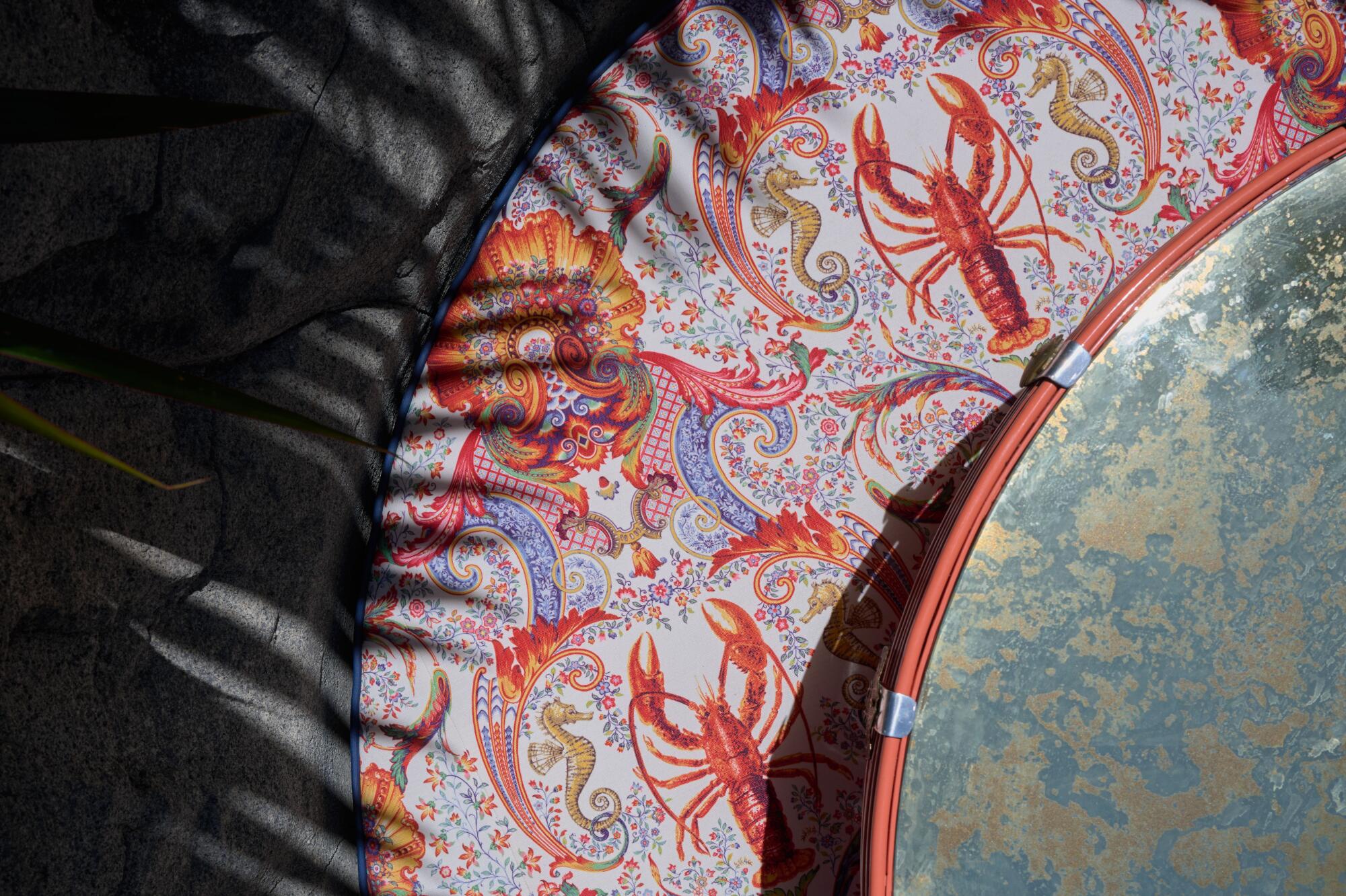 This view from above at the Night Hawk restaurant space shows a stone booth, elaborately patterned cushion and table top.