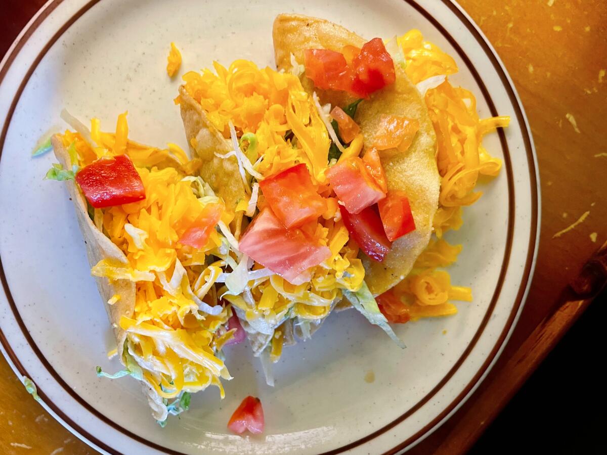 Three hard shell tacos on a plate.