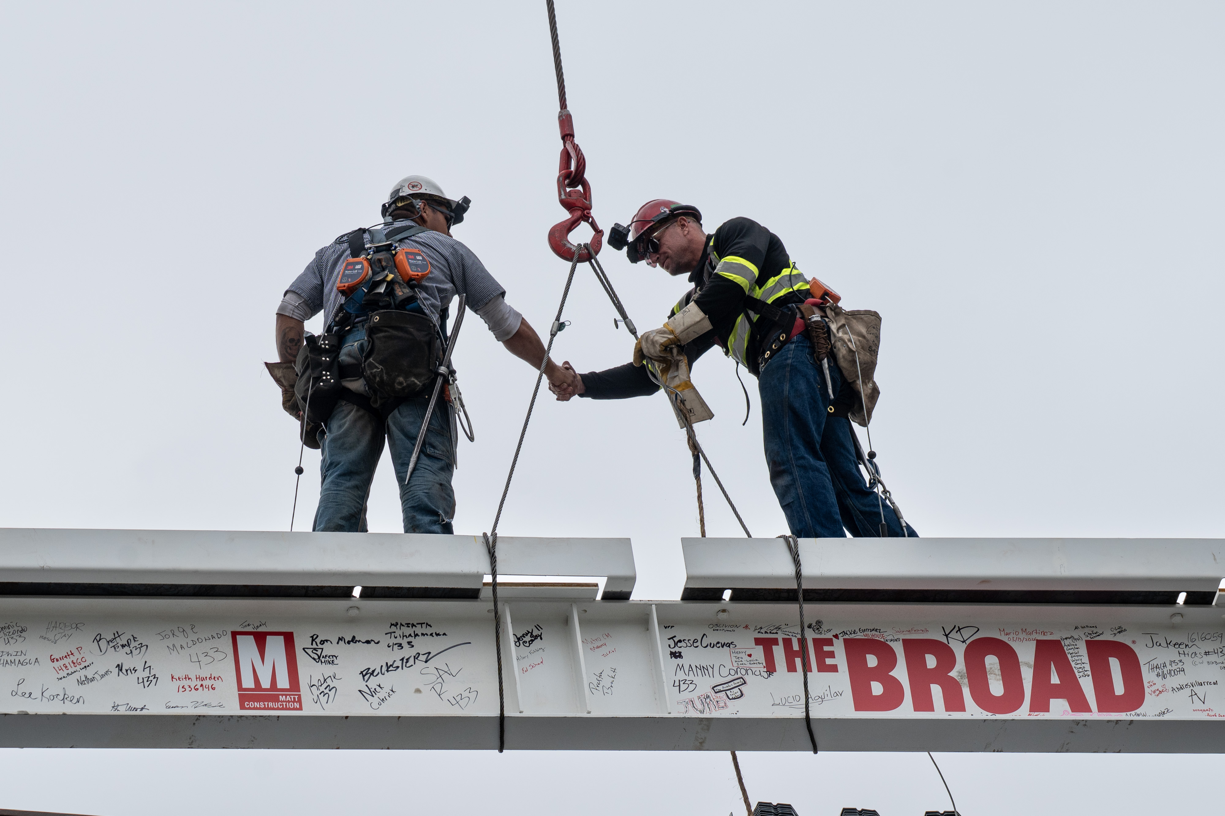 Workers place the last steel beam on top of the...