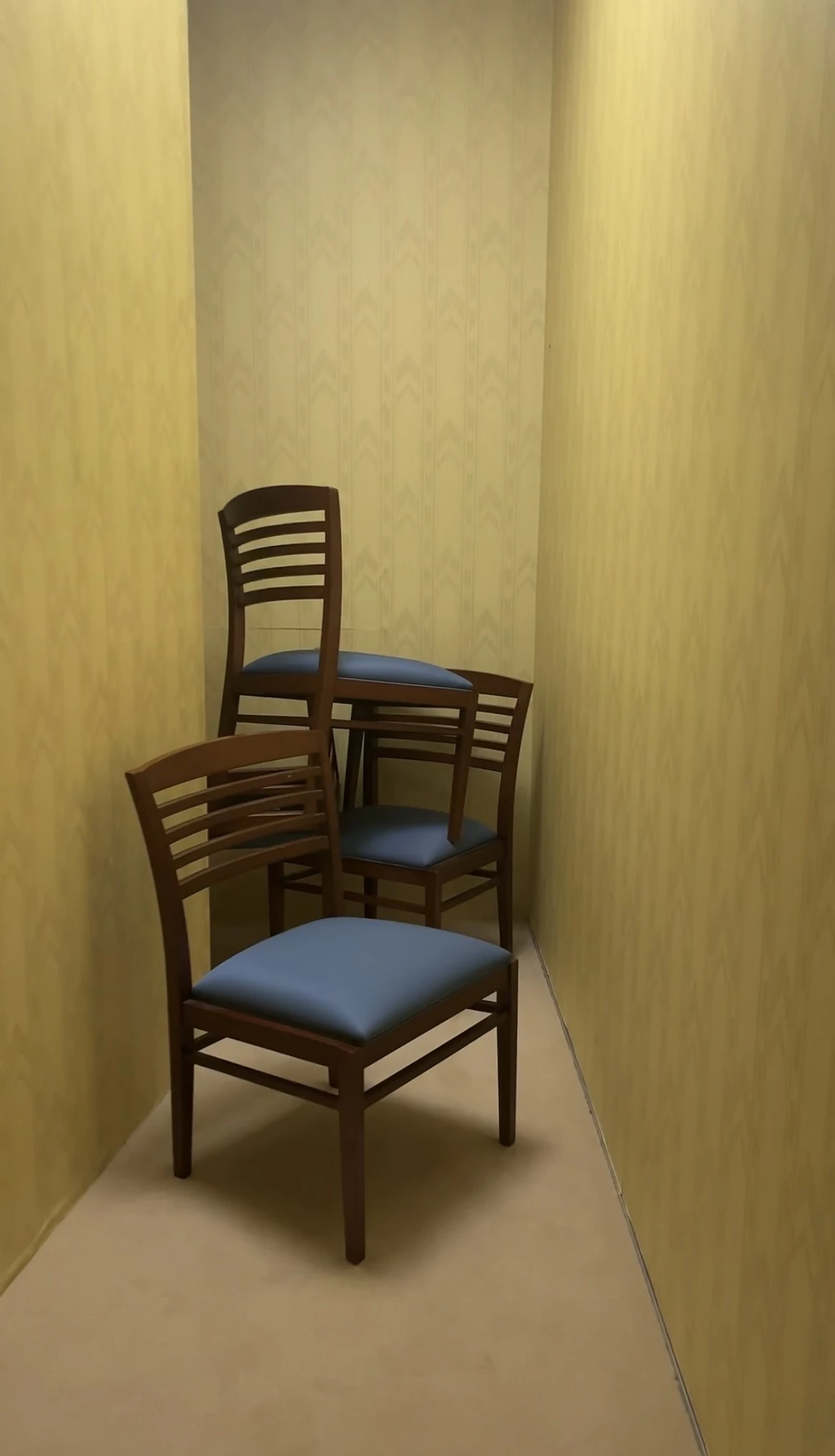 Chairs piled up in a narrow yellow hallway.
