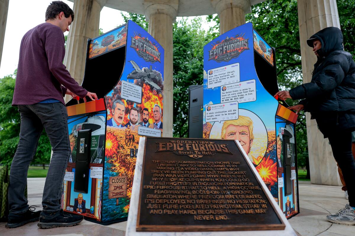 People play a satirical video game installation titled “Operation Epic Furious Strait to Hell"