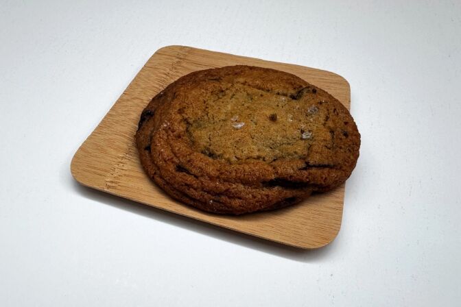 A close-up of a chocolate chip cookie lying on a small plate.