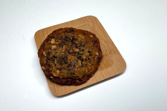 A close-up of a chocolate chip cookie lying on a small plate.