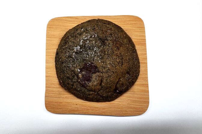 A close-up of a chocolate chip cookie lying on a small plate.