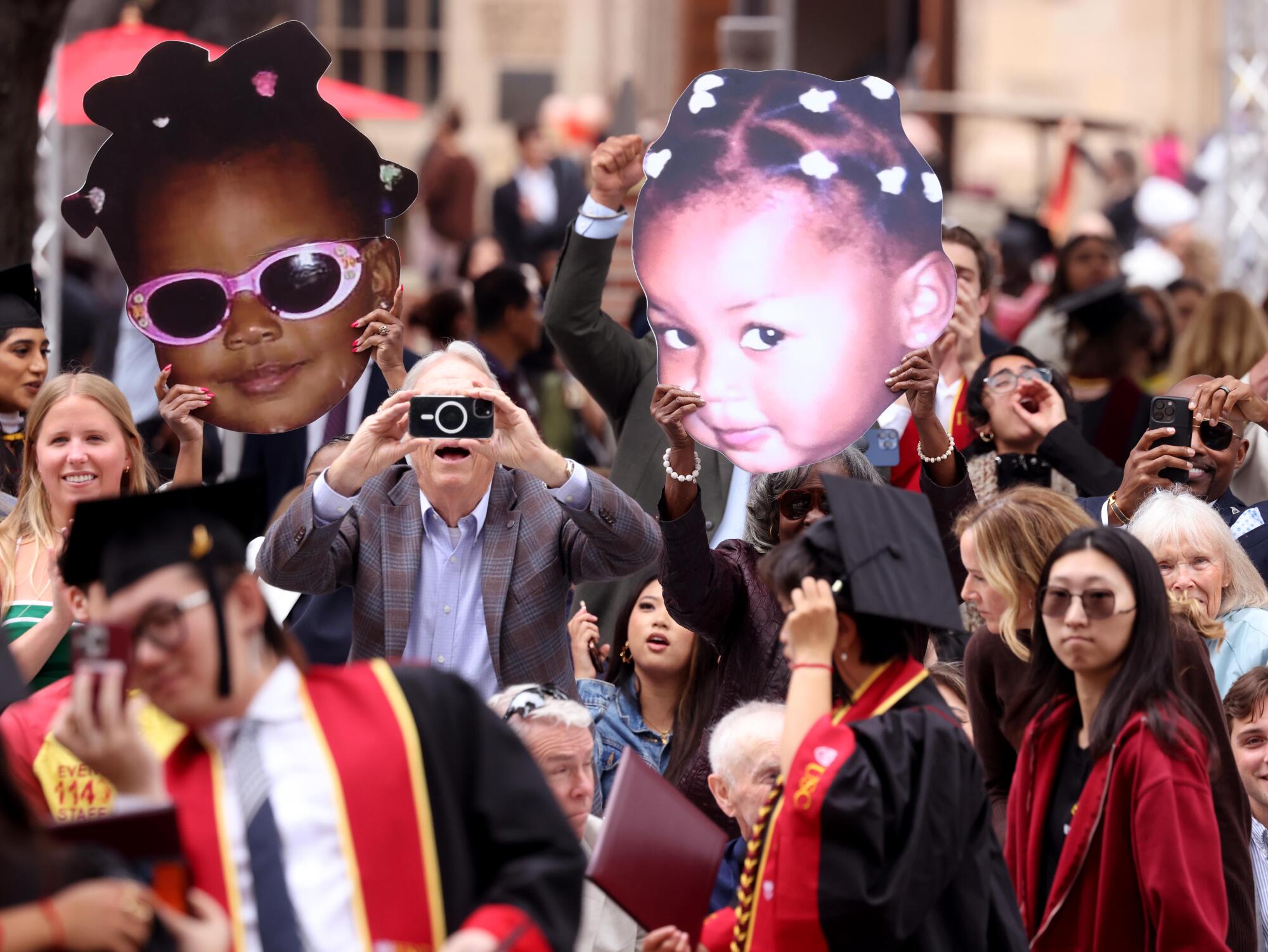 Parents, friends and relatives of graduates snap photos and wave baby pictures of graduates.