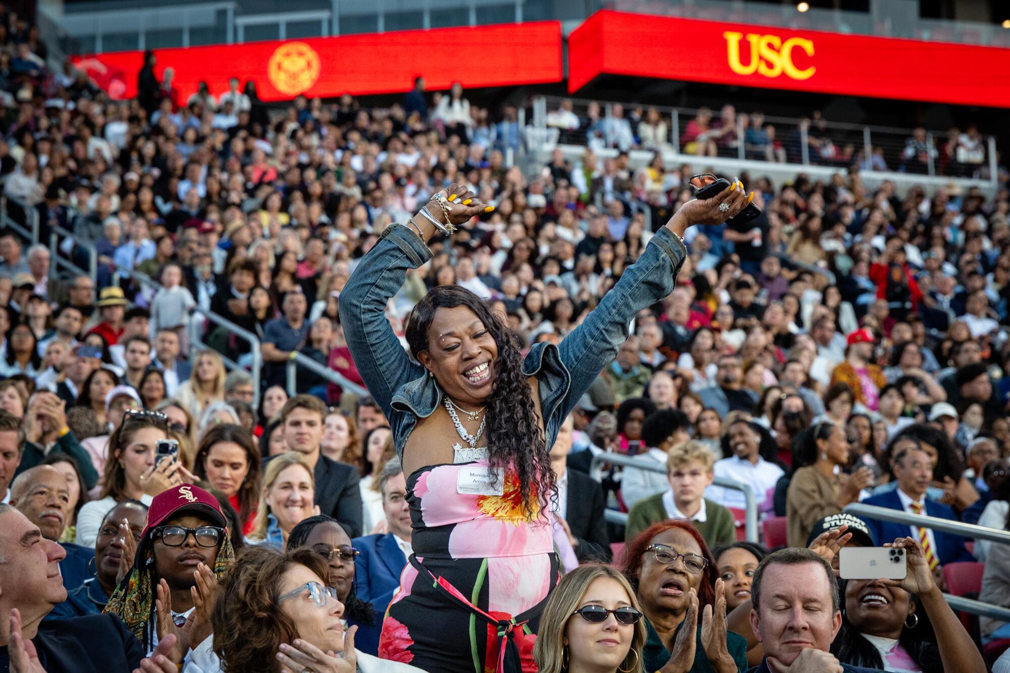 A family member of student commencement speaker Malique "Kash" Amos stands and waves arms during his speech.