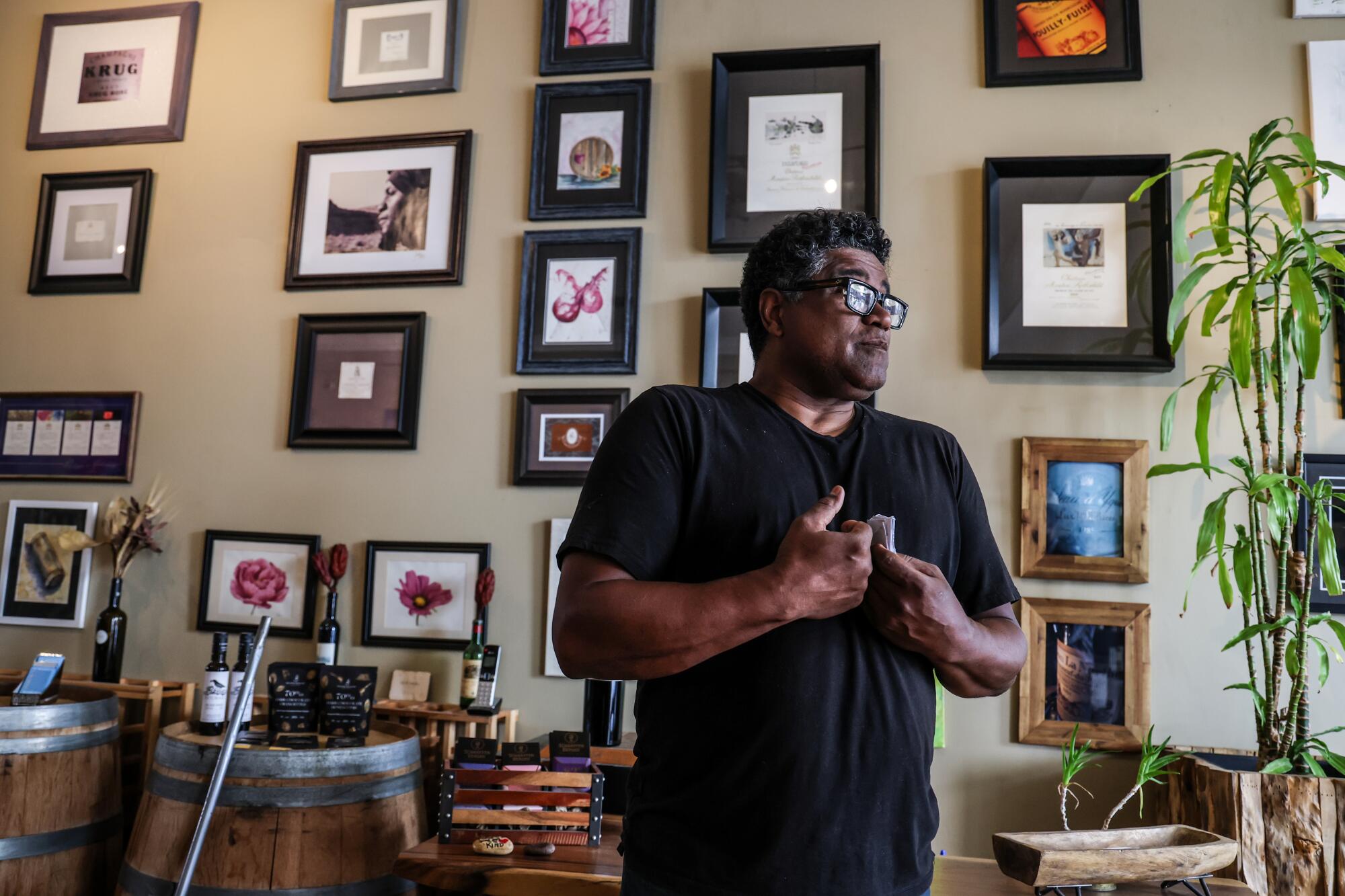 A man stands in front of a wall full of framed pictures