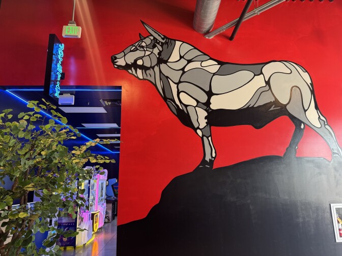 A mural of a bull in various shades of gray against a red backdrop.