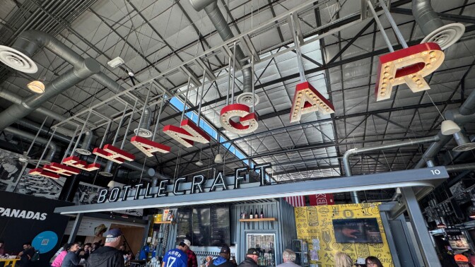 A sign that says "The Hangar" hanging from above the ceiling inside a warehouse-like space.