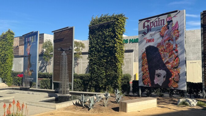 A sunny, spacious patio with giant posters of travel destinations standing next to benches.
