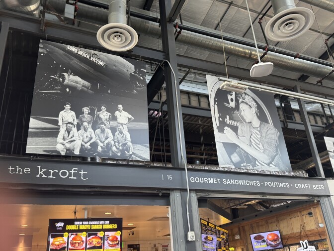 Interior shot of a food hall, showcasing two giant photos of aviation history in Long Beach