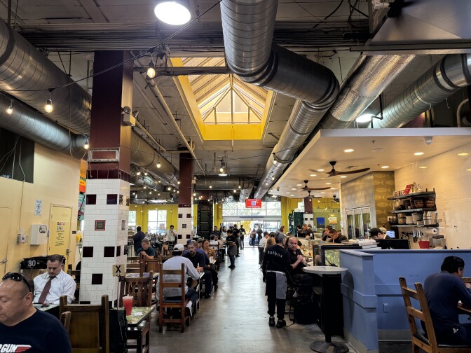A large food hall with tables and chairs and lots of people eating.