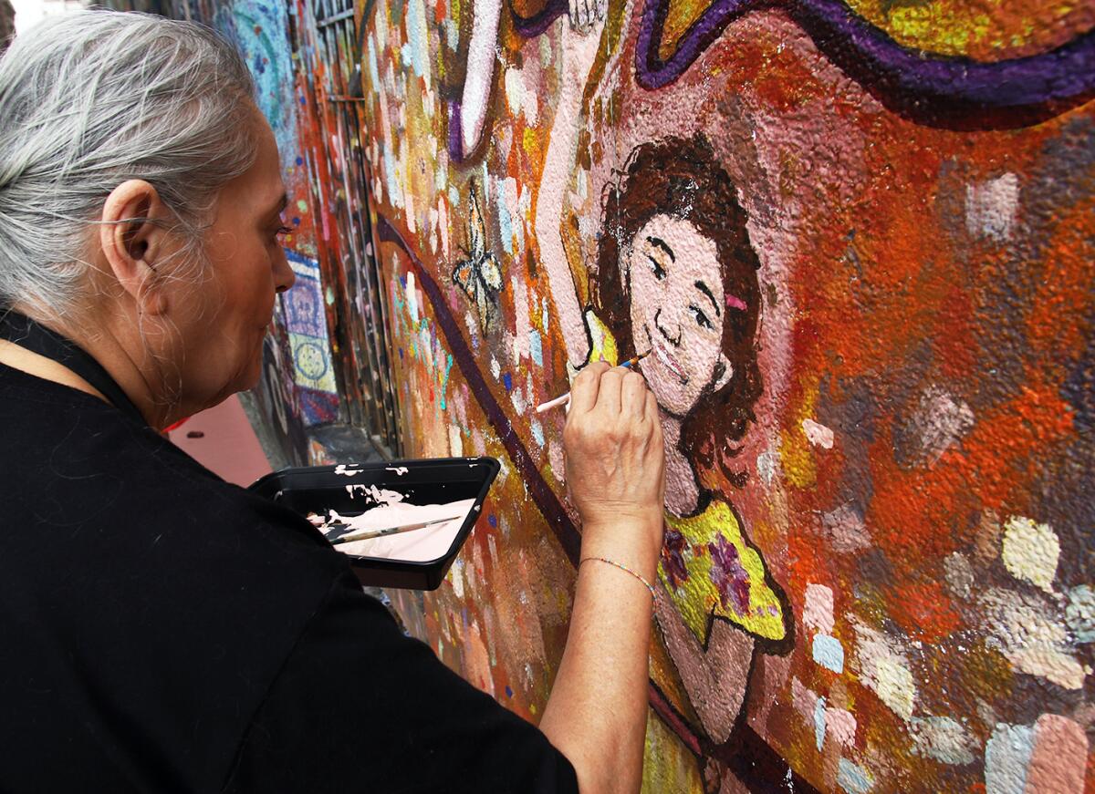 Maria Reyna, of Irvine, takes part in restoring "Viva Santa Ana," a mural in Santa Ana.