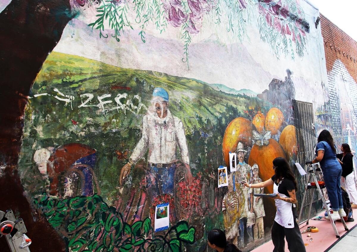 Volunteers restore "Viva Santa Ana" a mural created by the Santa Ana Community Artist Coalition to honor local history.