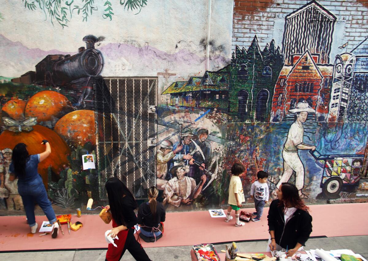 A group of volunteers take part in restoring "Viva Santa Ana" a mural in Santa Ana on Saturday, May 2, 2026.