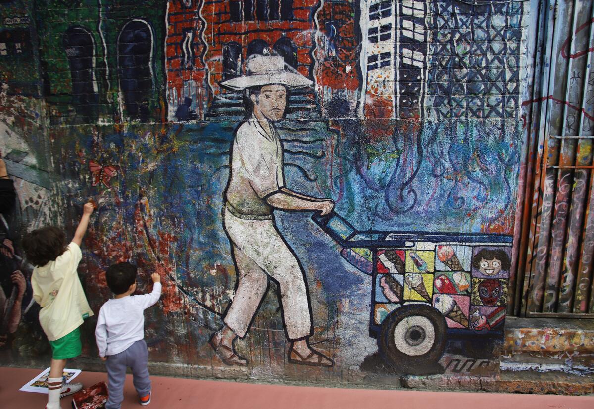 Children take part in restoring "Viva Santa Ana" a mural in Santa Ana on Saturday, May 2, 2026. 